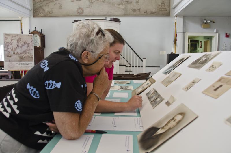 Mattapoisett native Natalie Hemingway and Curator Elizabeth Hutchinson inspect photos at the recent exhibit. BY GEORGIA SPARLING